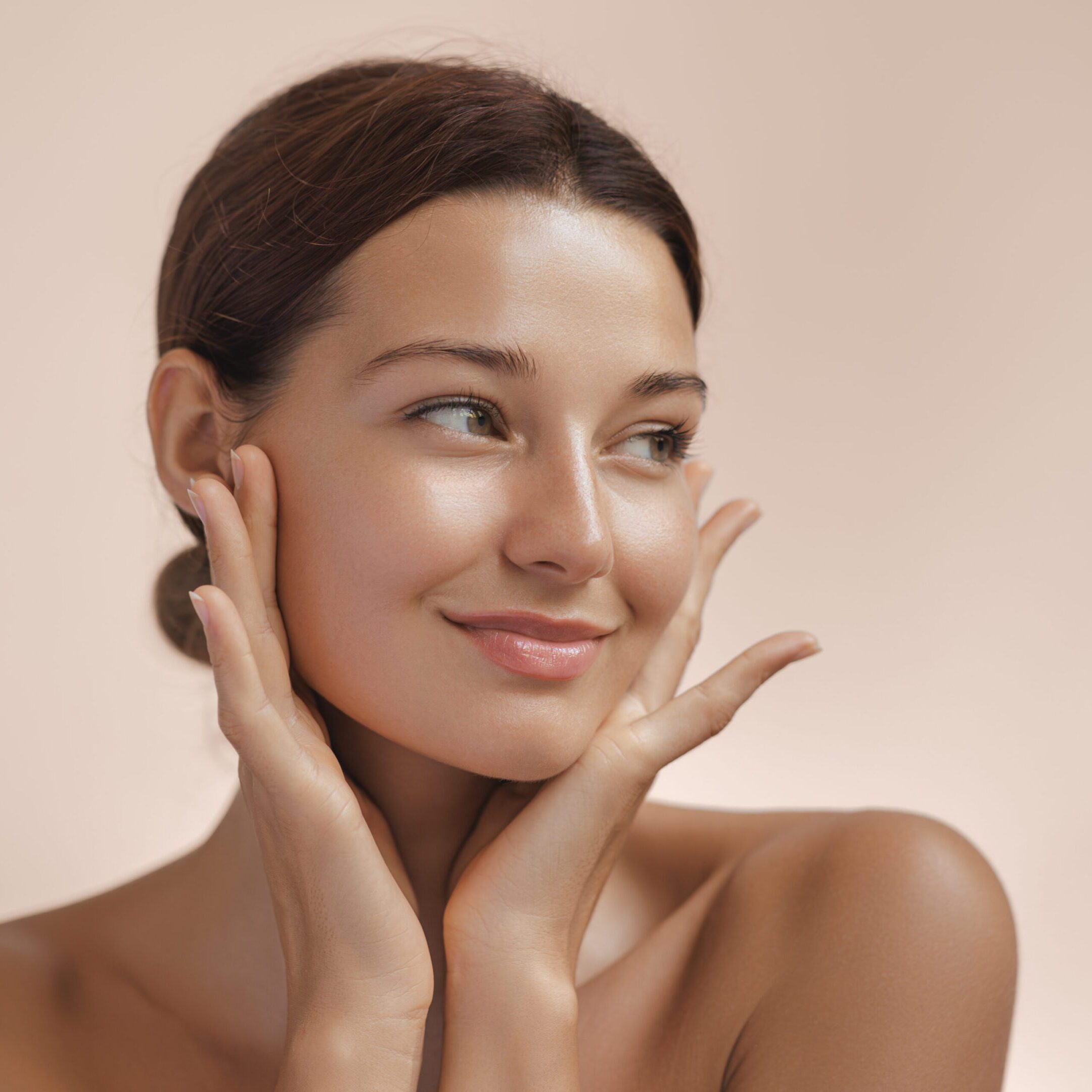 Happy beautiful young adult woman showing her perfect face with healthy shiny skin. Beauty photo of gorgeous girl after morning beauty cosmetic routine finishes daily makeup on pink background. Youth and skin care concept. High-quality studio photo