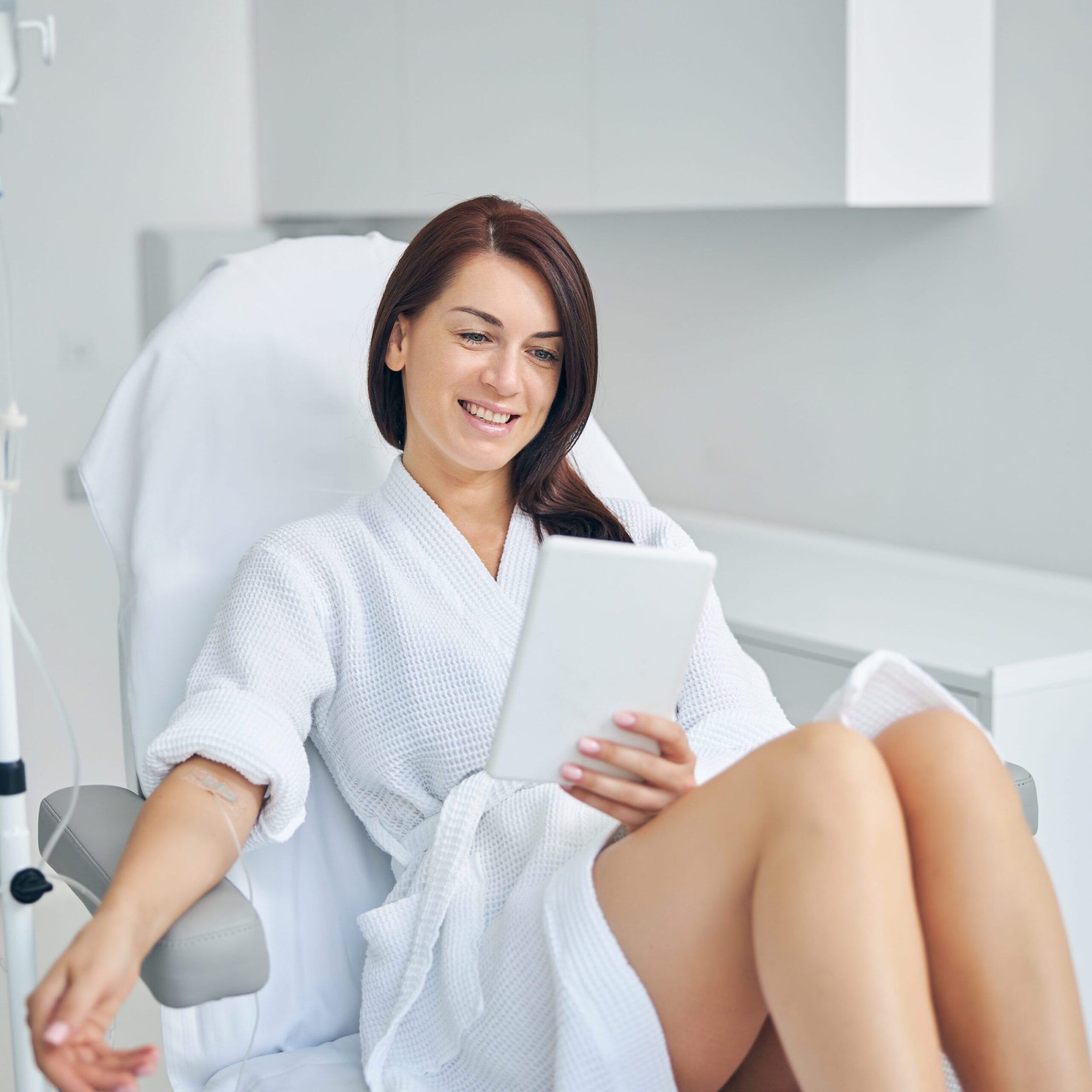 Smiling woman with dark hair getting an intravenous vitamin drip treatment at a beauty salon