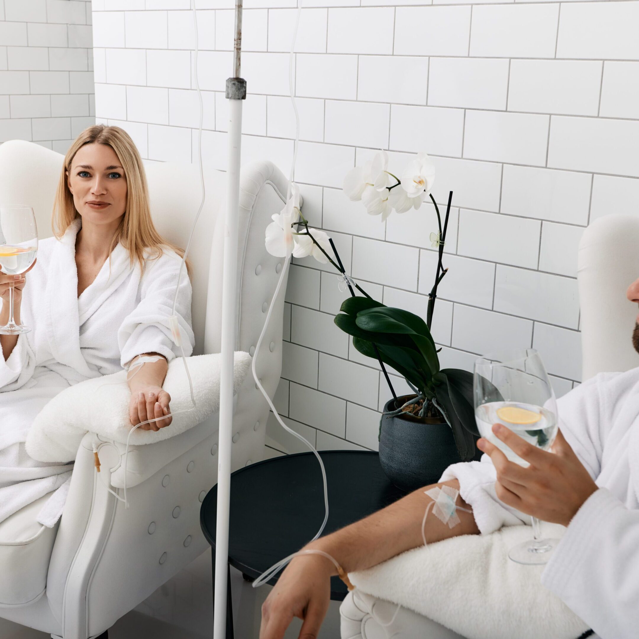 Couple in love during intravenous vitamin therapy. Beautiful woman with her boyfriend with glasses of refreshing drink with lemon in medical clinic for detox their organisms