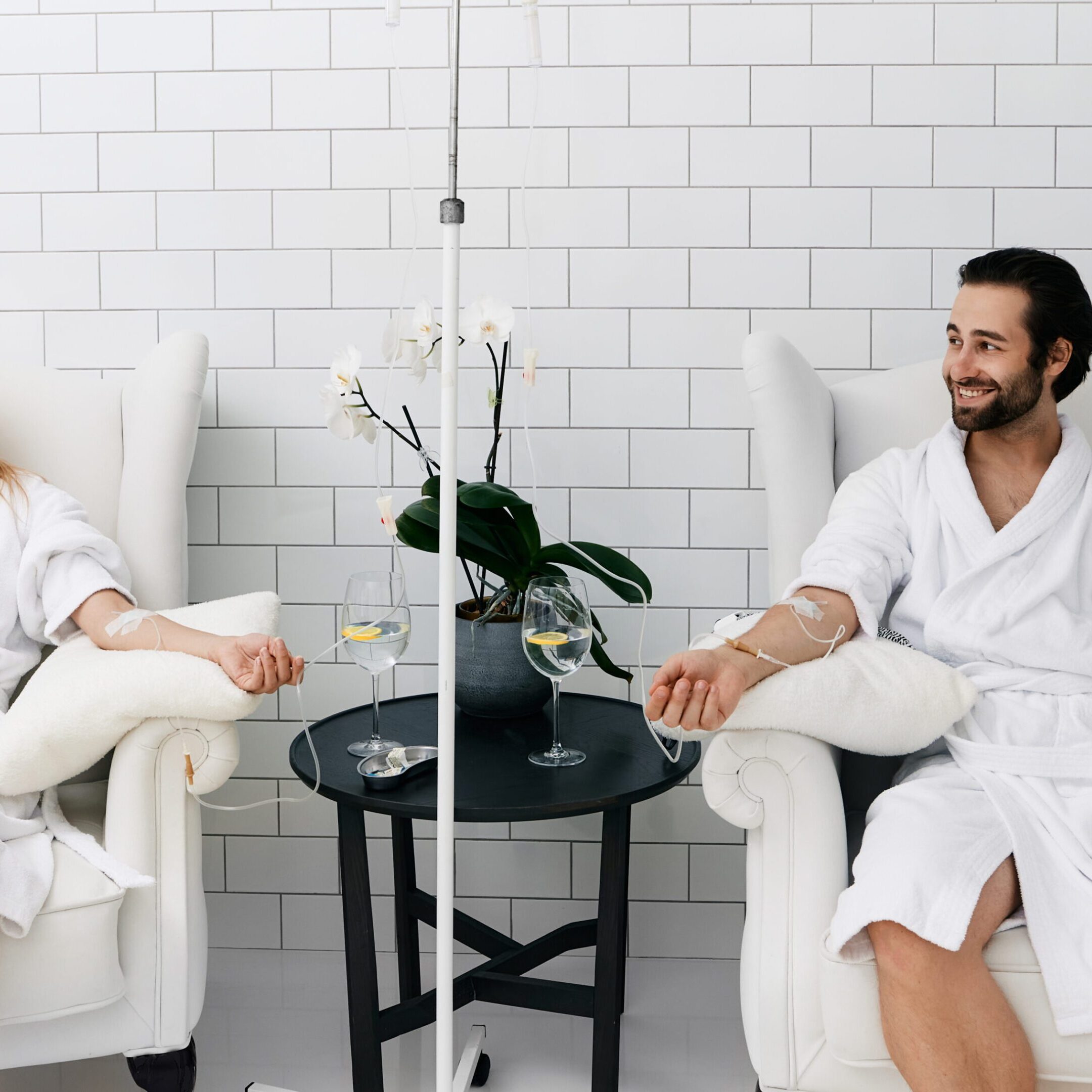 Maintenance and restoration of human immune system with vitamin IV infusion therapy. Beautiful woman with her boyfriend in modern wellness center during intravenous vitamin therapy.