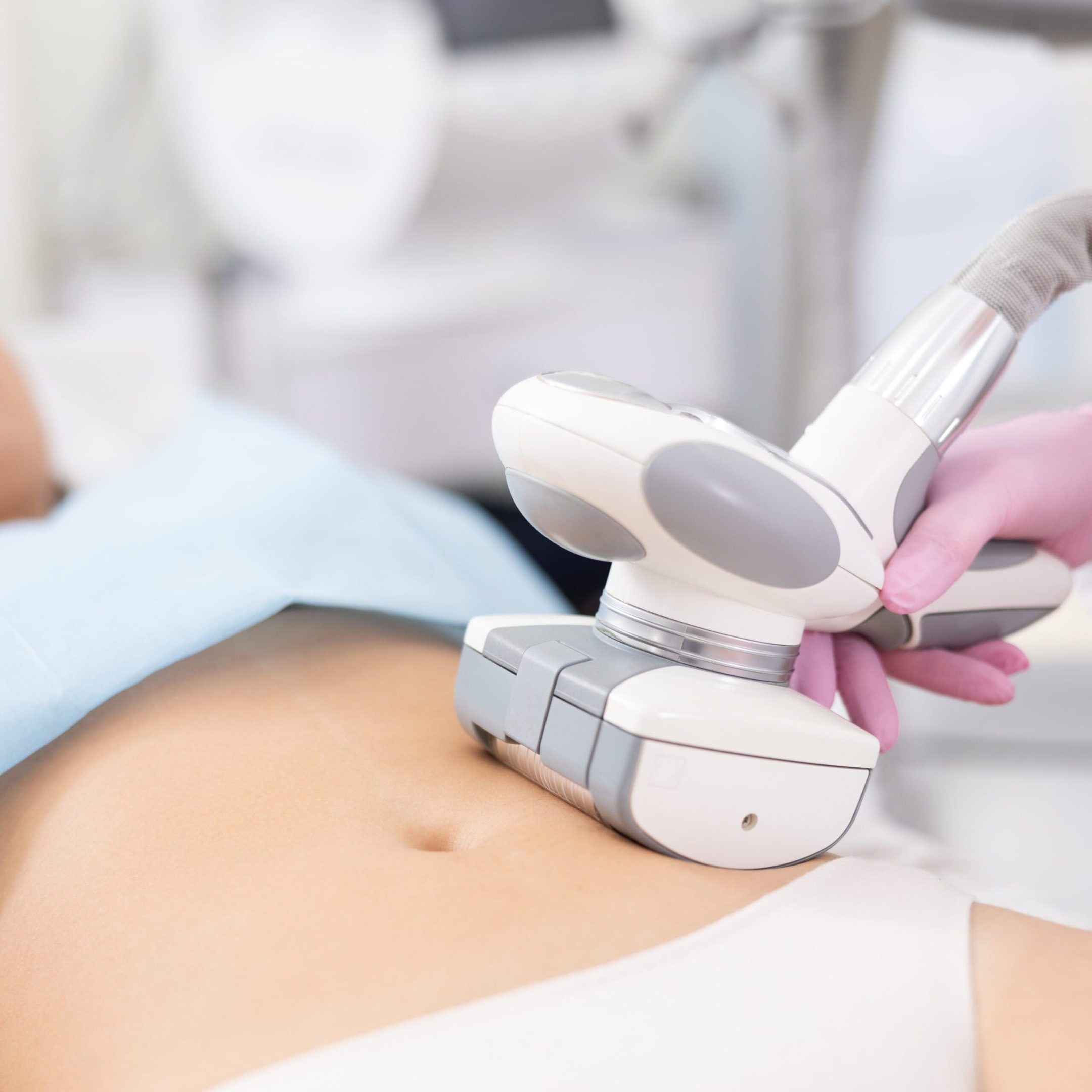Unrecognizable masseur performing anti cellulite massage for belly of young woman in aesthetic medicine clinic Young woman getting ultrasound cavitation body contouring treatment, anti-cellulite therapy, vacuum massage from unrecognizable cosmetologist. Hardware cosmetology for body sculpting