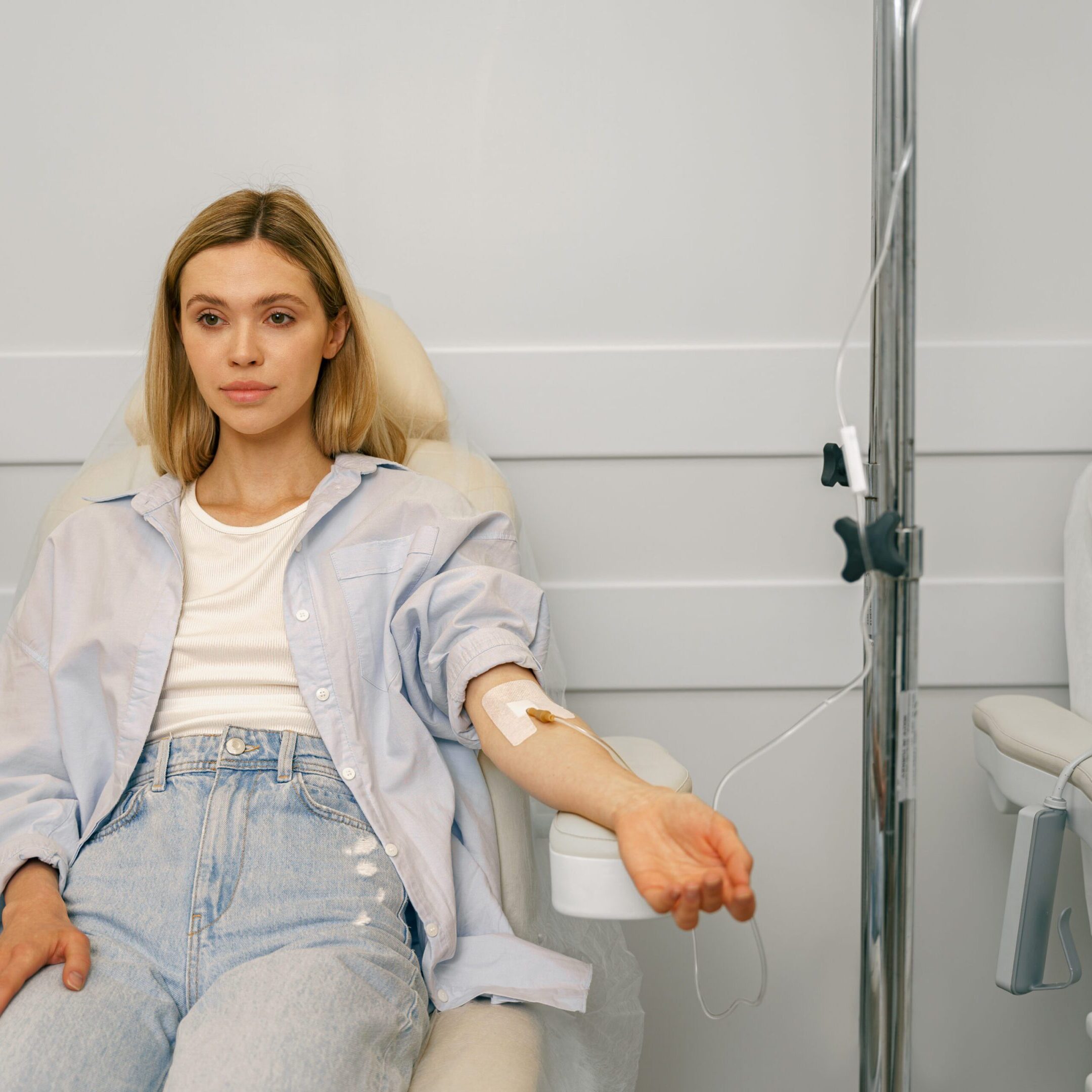 Woman sitting in armchair while receiving IV infusion in hospital. High quality photo