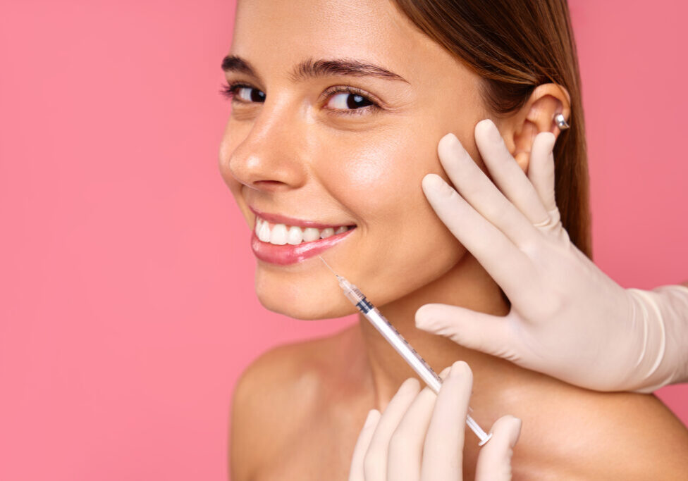 The image depicts a woman undergoing a cosmetic procedure for lip enhancement or skin rejuvenation with injectables in a clinical setting, aiming to enhance her lips appearance and youthfulness